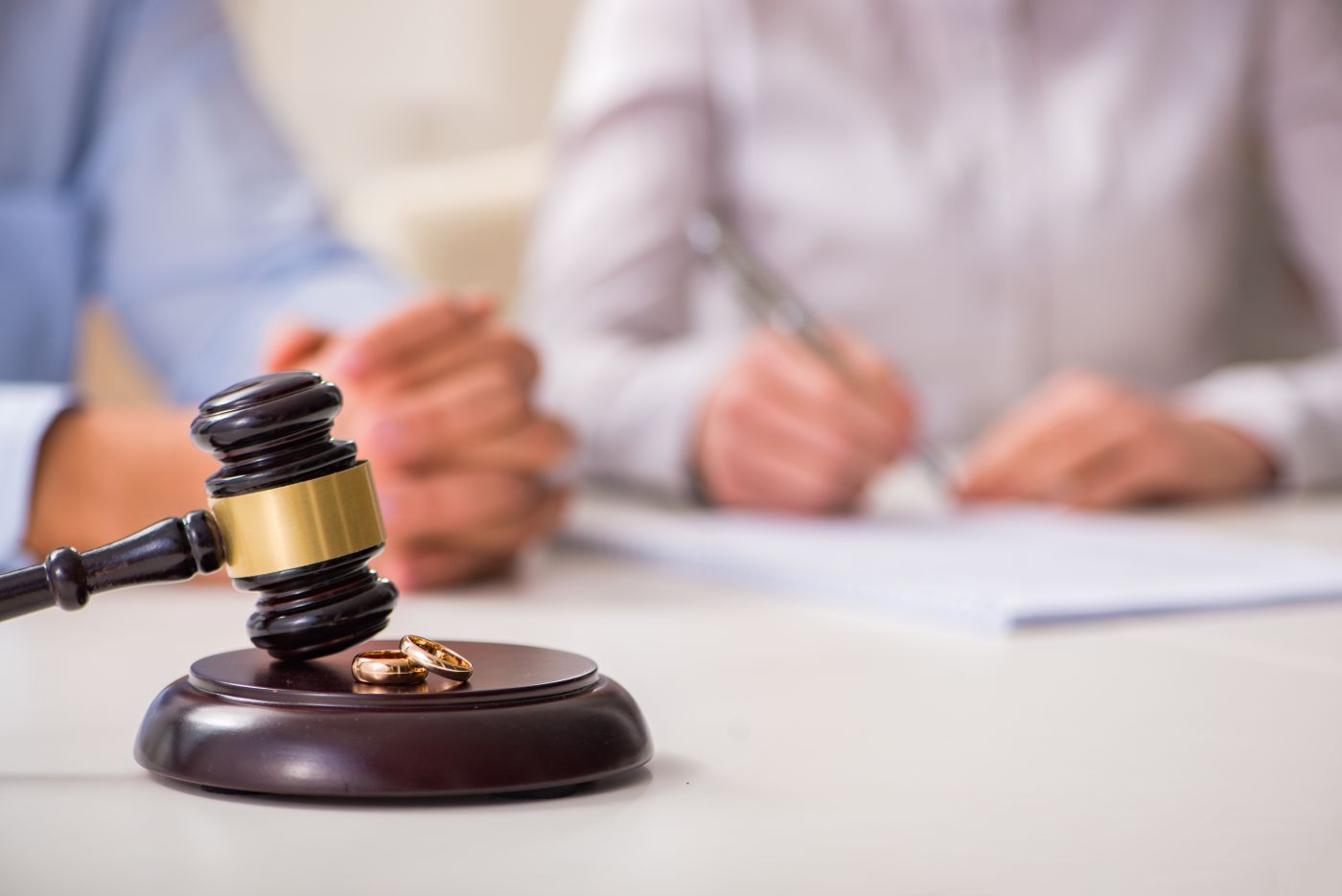 Gavel with wedding ring and couples signing divorce decree