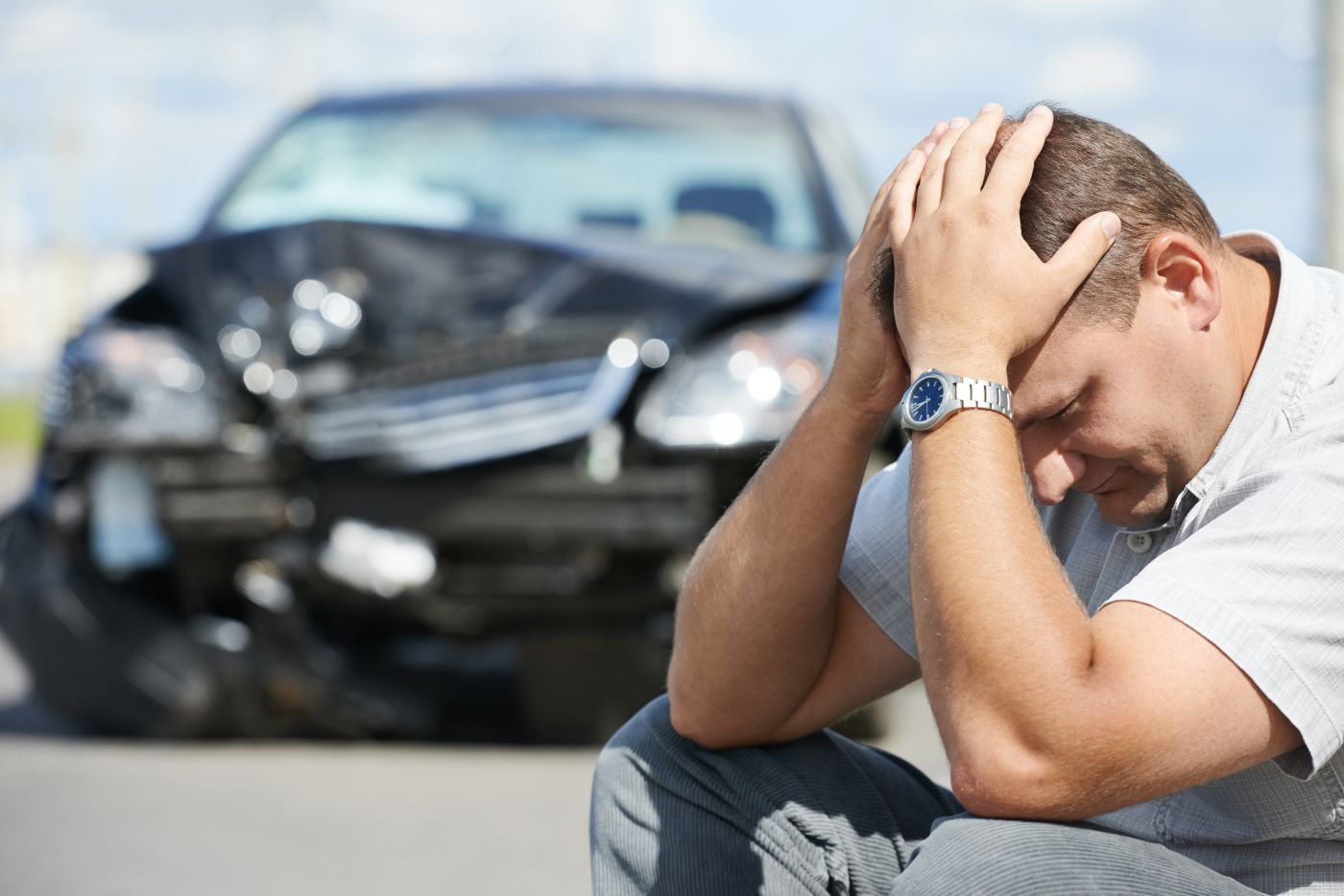 Upset man sitting in road after car accident
