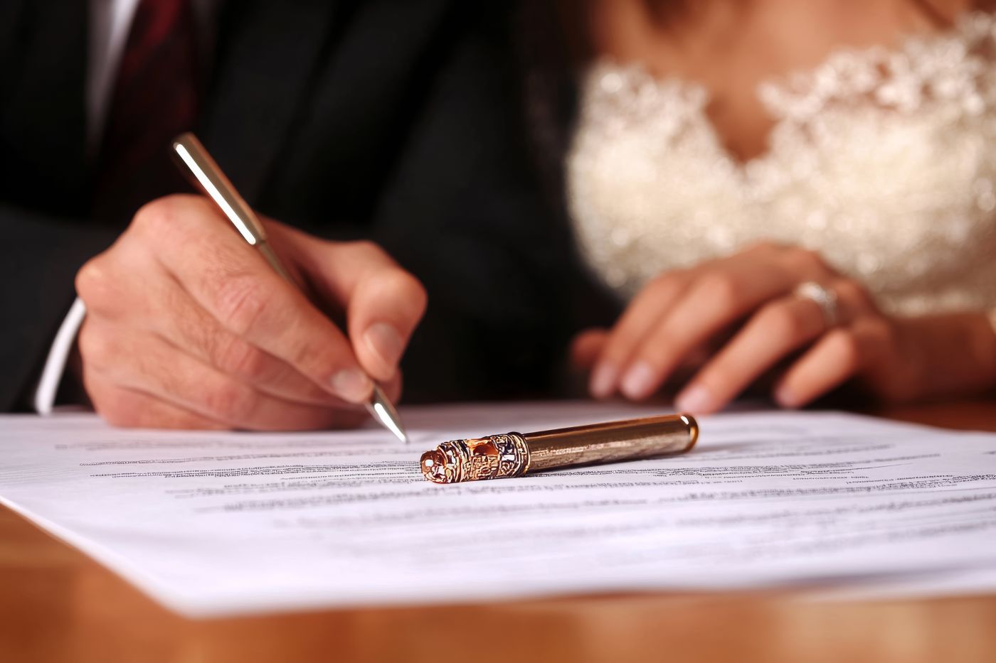 Groom and bride carefully reviewing and signing prenuptial agreement