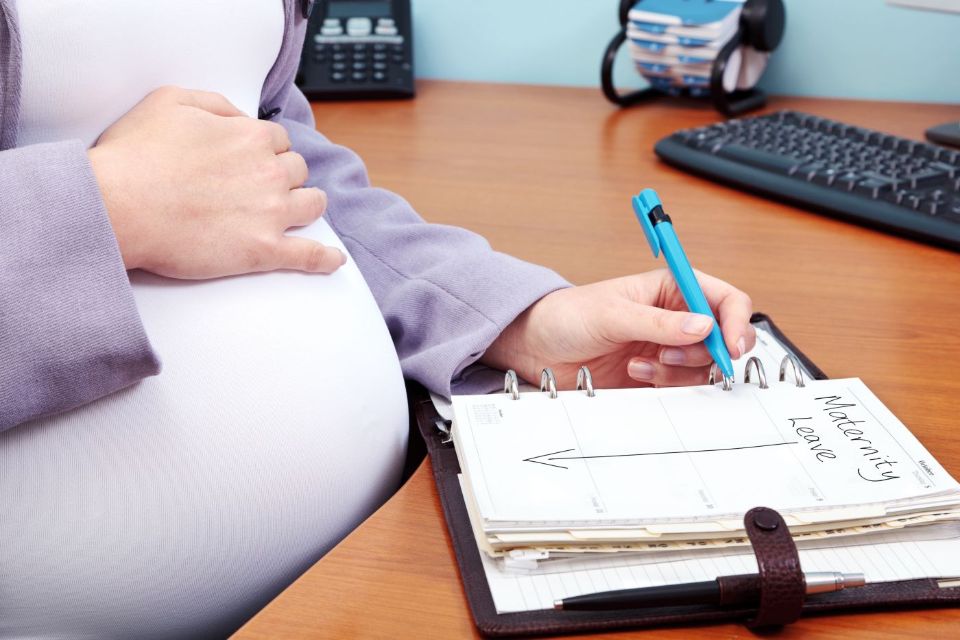 Women writing Maternity Leave on notebook