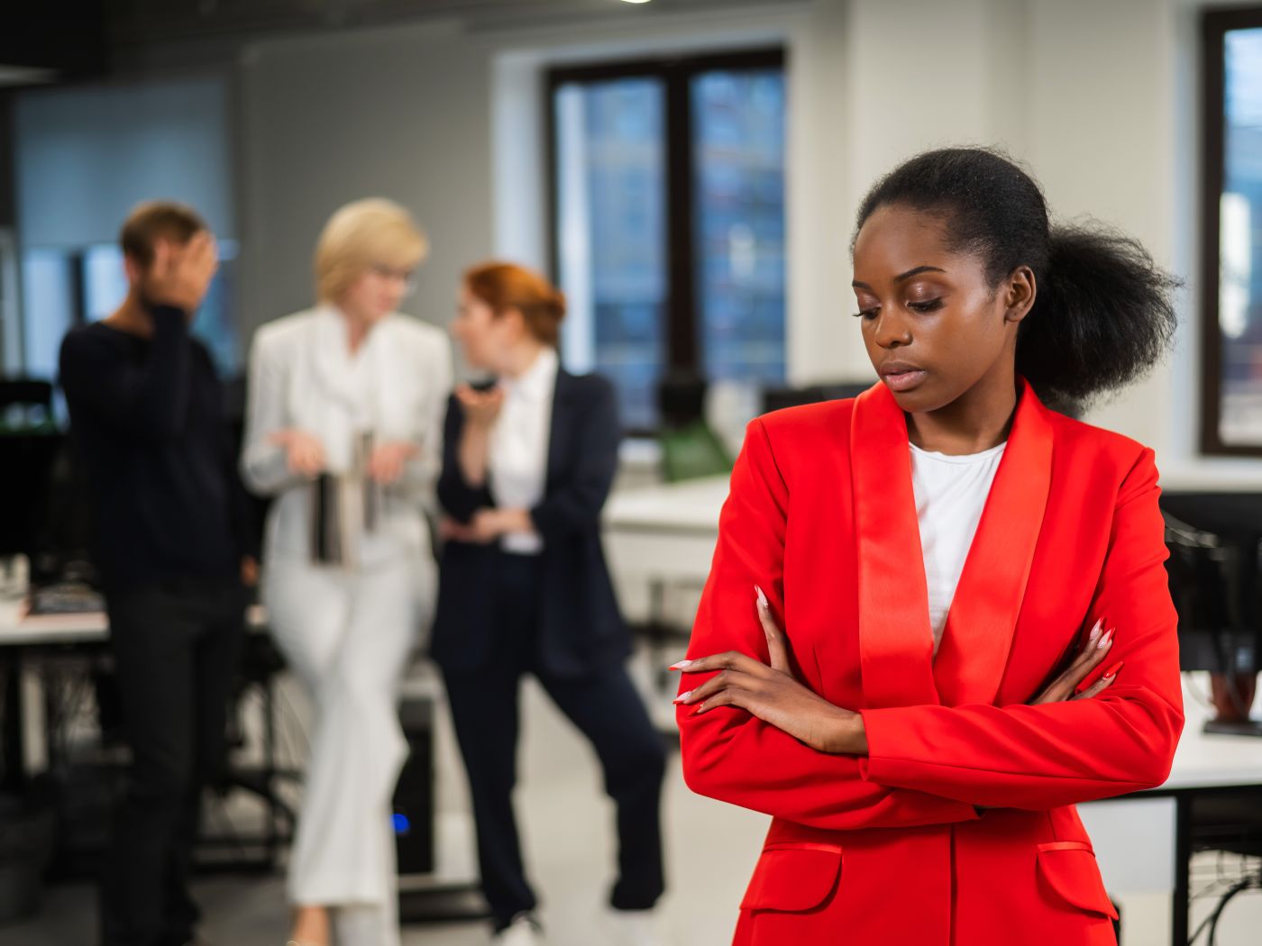 Isolated dark-skinned women in office with colleagues talking behind her back