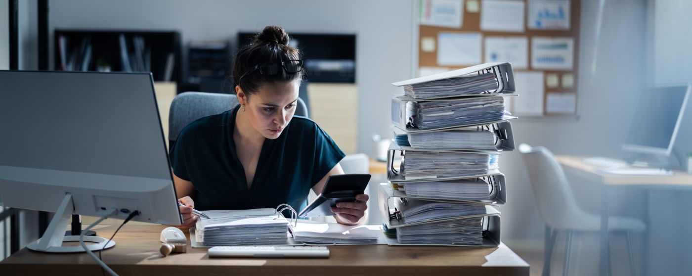 Women working at office with stack of folders beside her