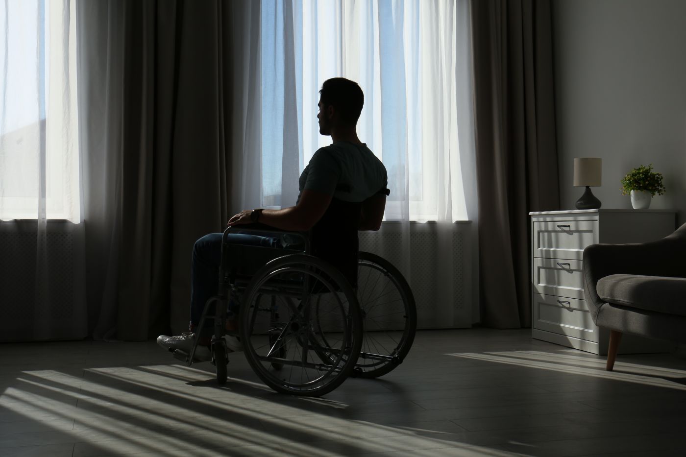 Young man sitting in wheelchair near window