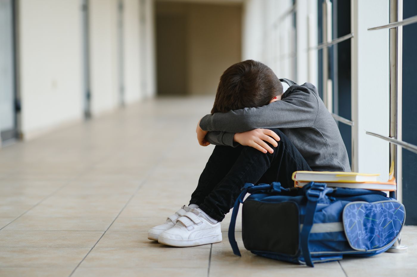 Sad child sitting in school corridor