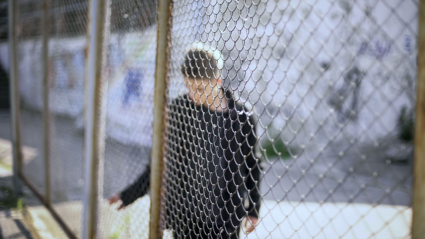 Young boy behind metal fence