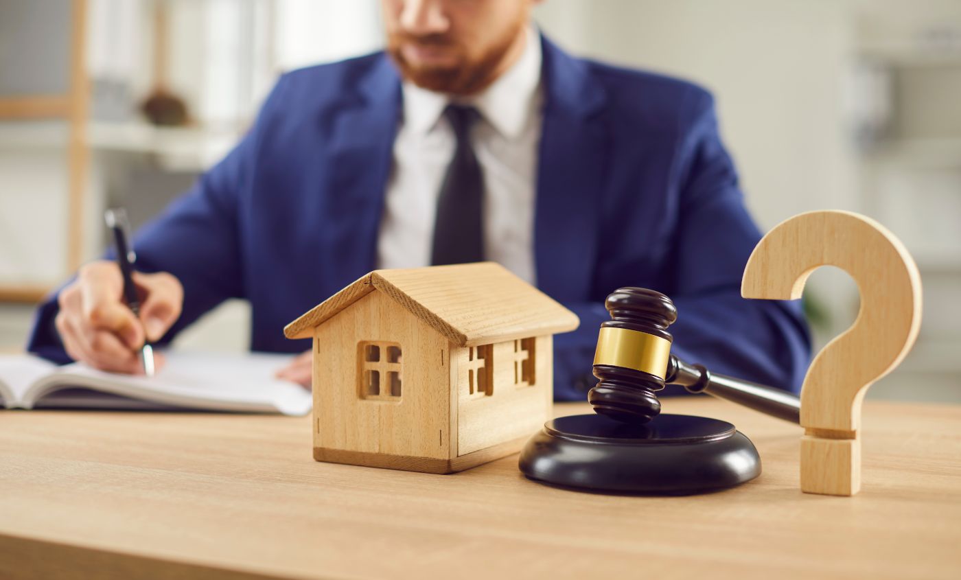 Question mark symbol next to gavel and house model with attorney