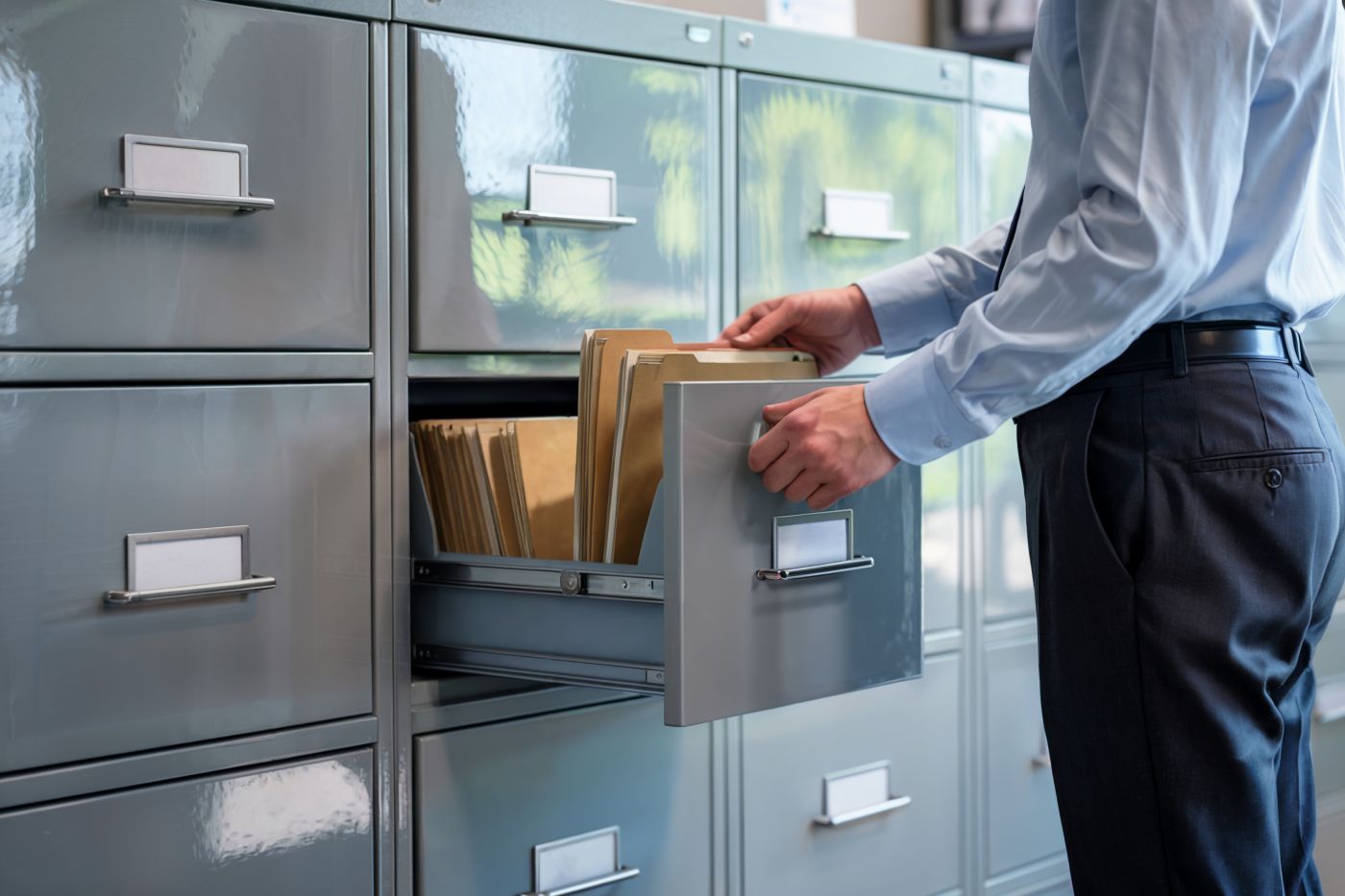 Business professional organizing files in a metal filing cabinet