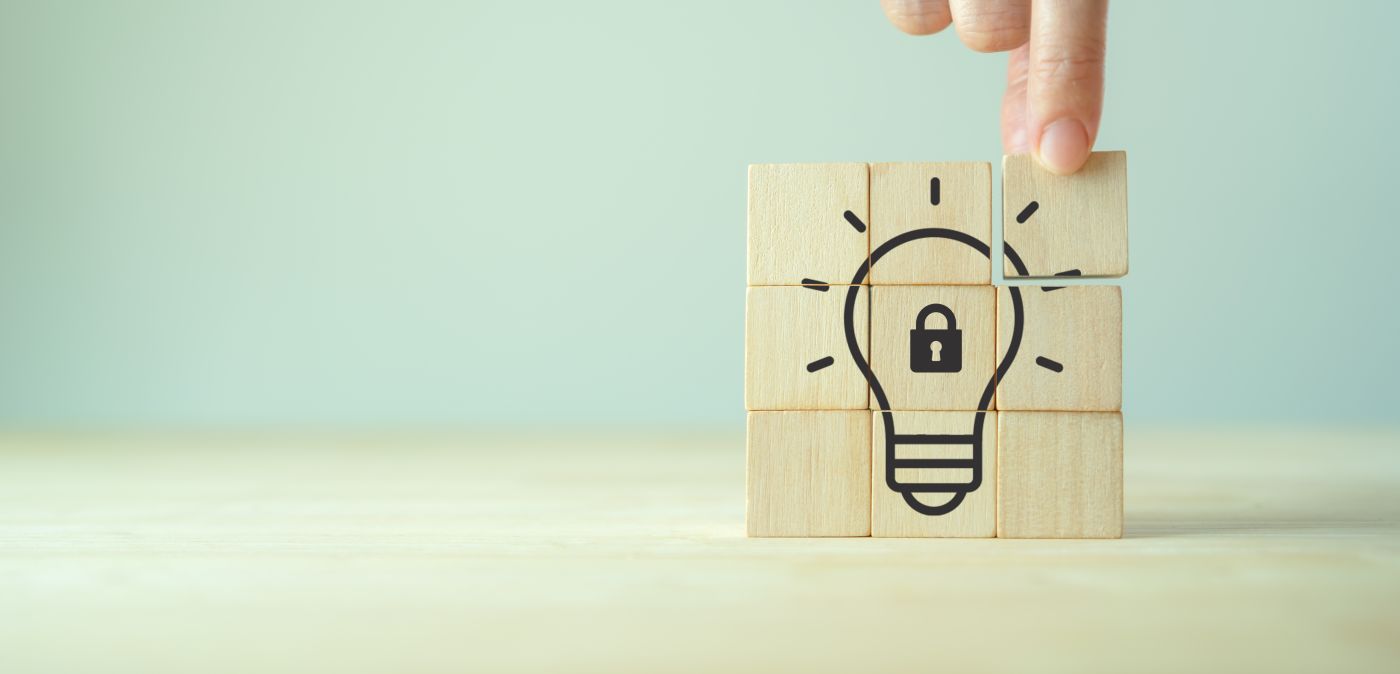 Hands arranging wooden block with bulb and lock symbol