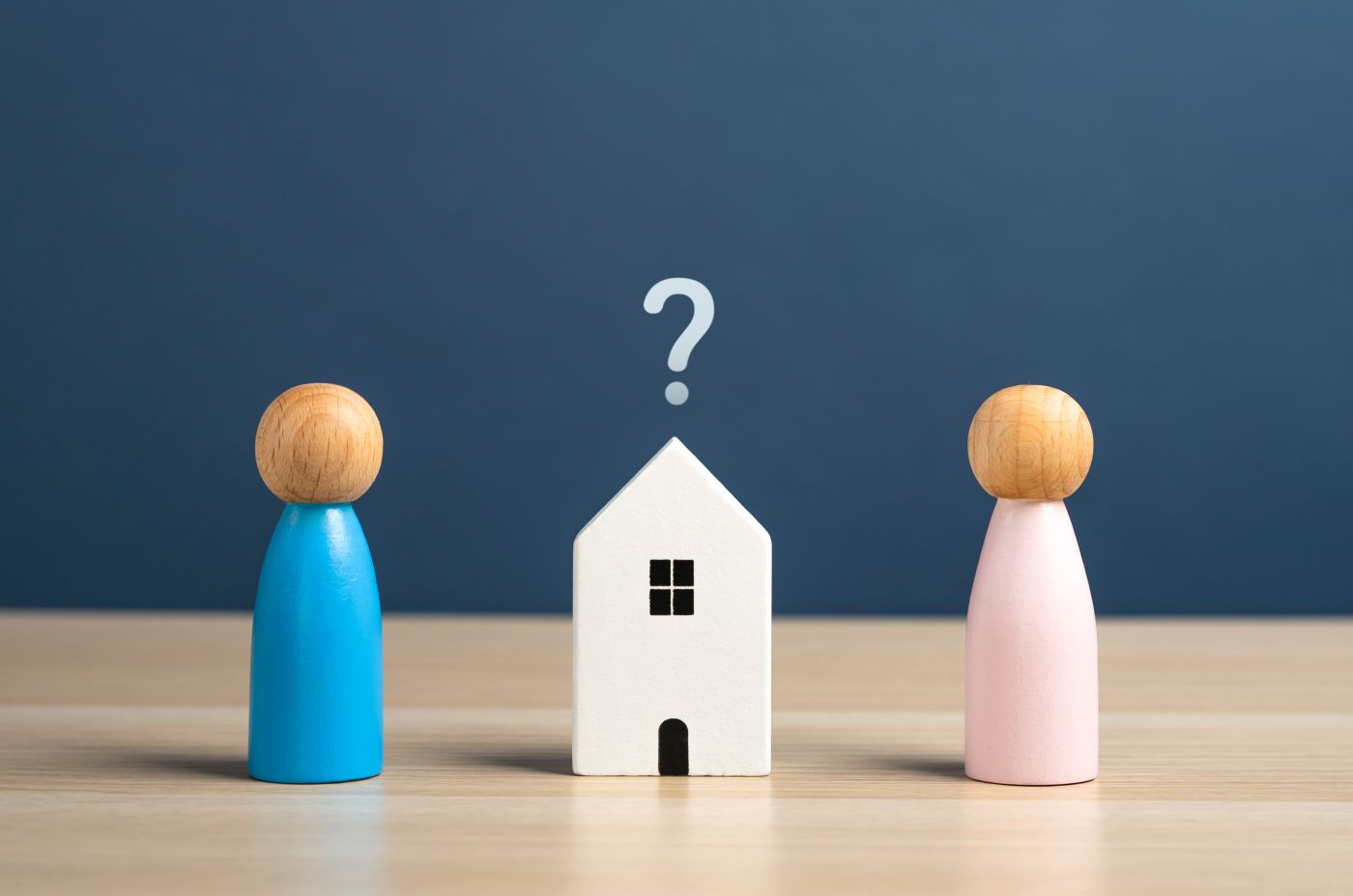 Que mark over house model in middle of two wooden figures