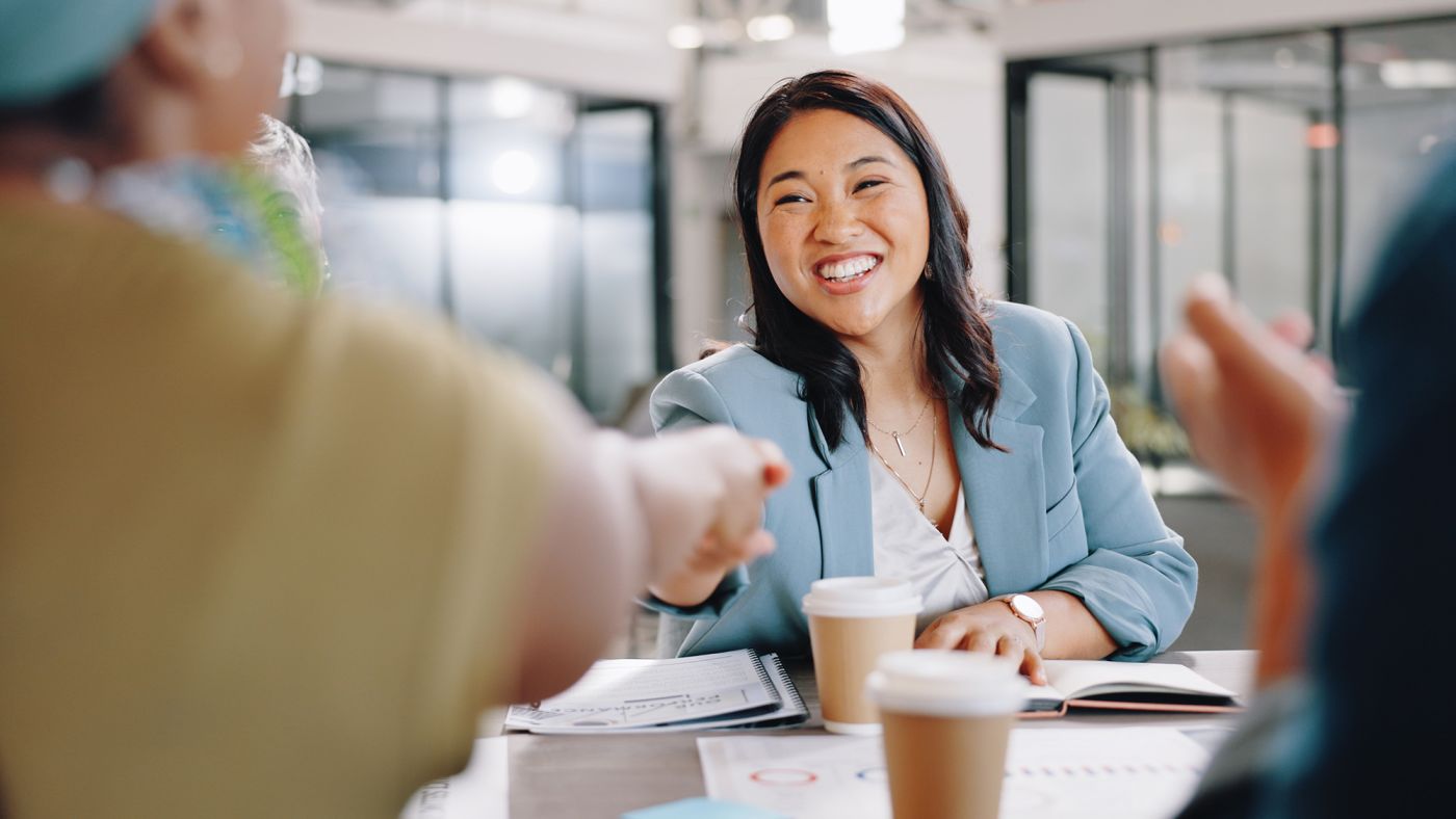 An Asian woman shaking hands with clients during a meeting
