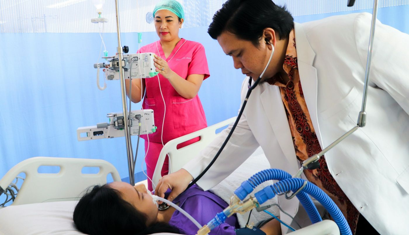 Hawaiian doctor and nurse treating an injured woman in hospital