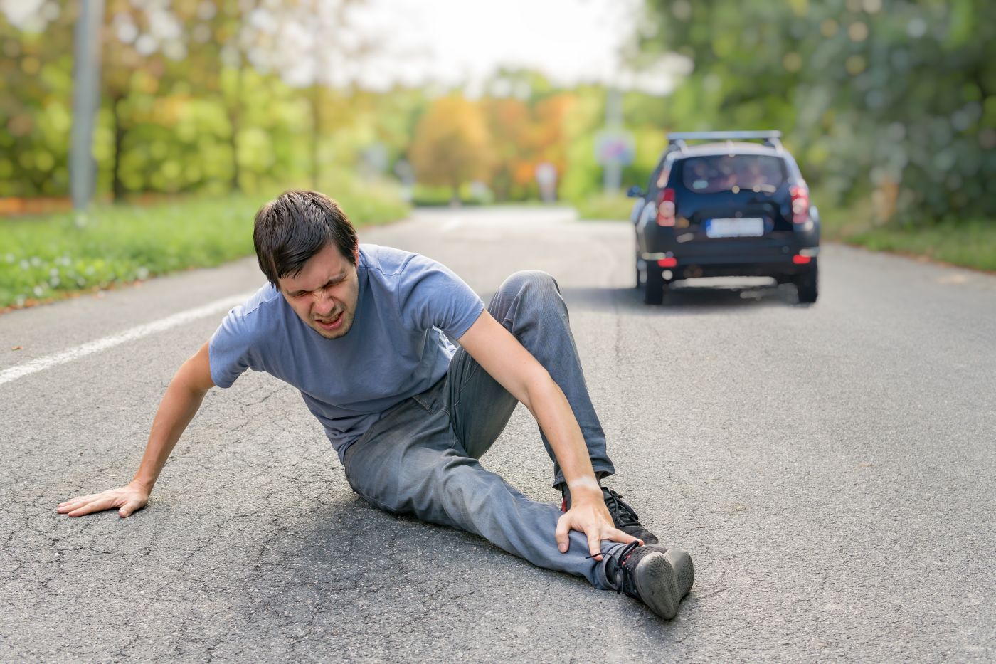 Injured man on road with fleeing car from accident site