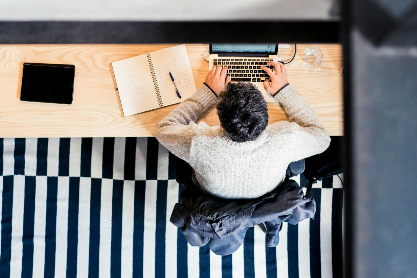 Aerial view of male employee at work recording notes on his laptop