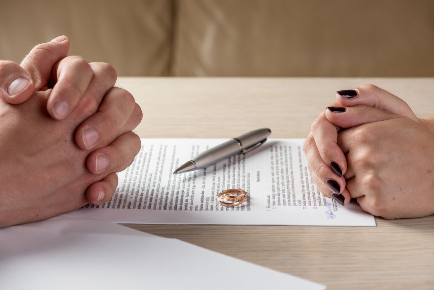 Couples with divorce paper, pen and wedding rings in table