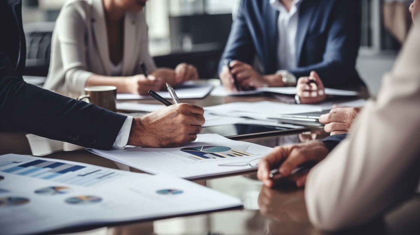 Paperwork and group of people's hands on a board room table