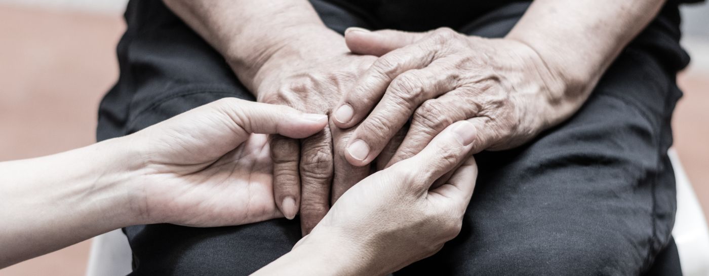 Caregiver holding hands of old man