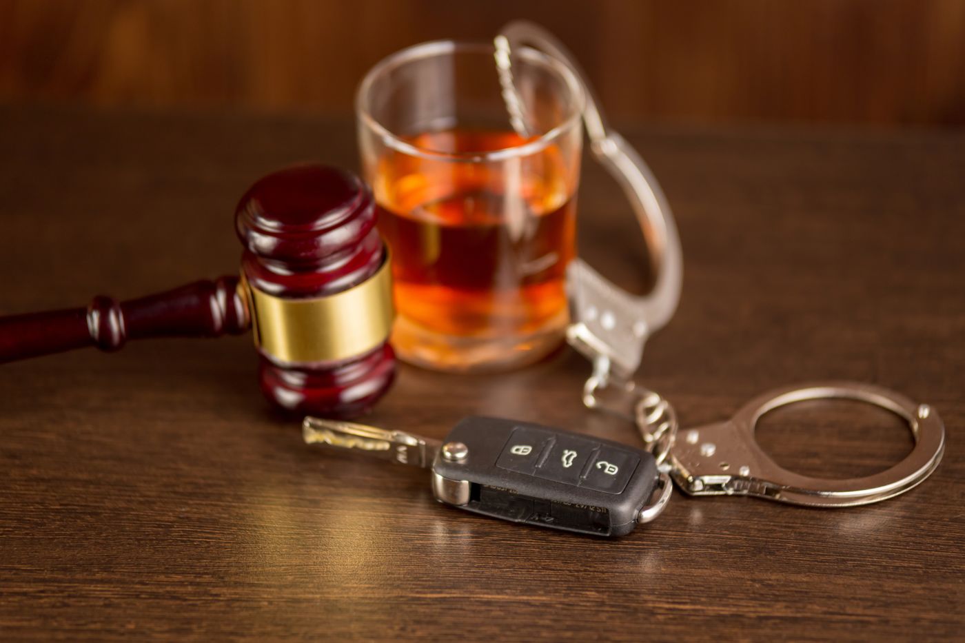 Car Keys, Glass of Alcohol, Handcuff and Gavel in table