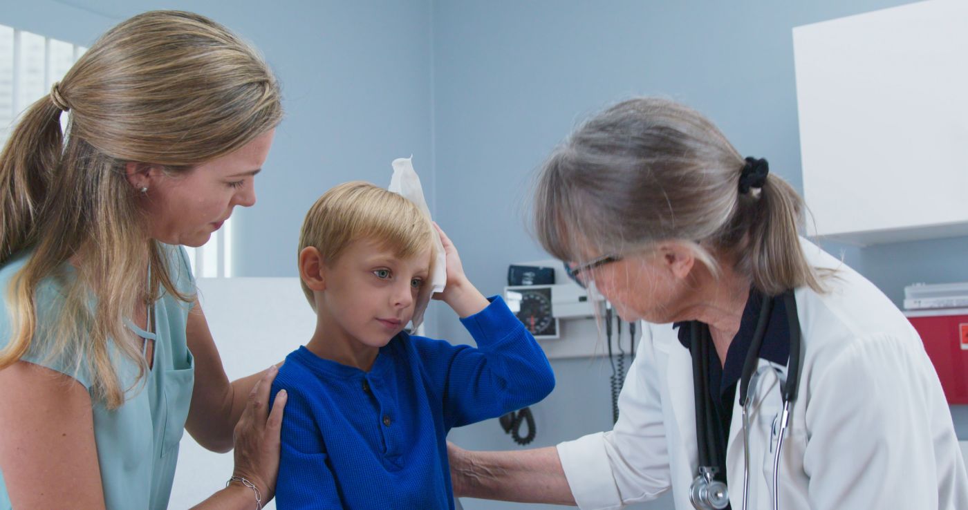 Child at pediatricians office holding ice pack on his head
