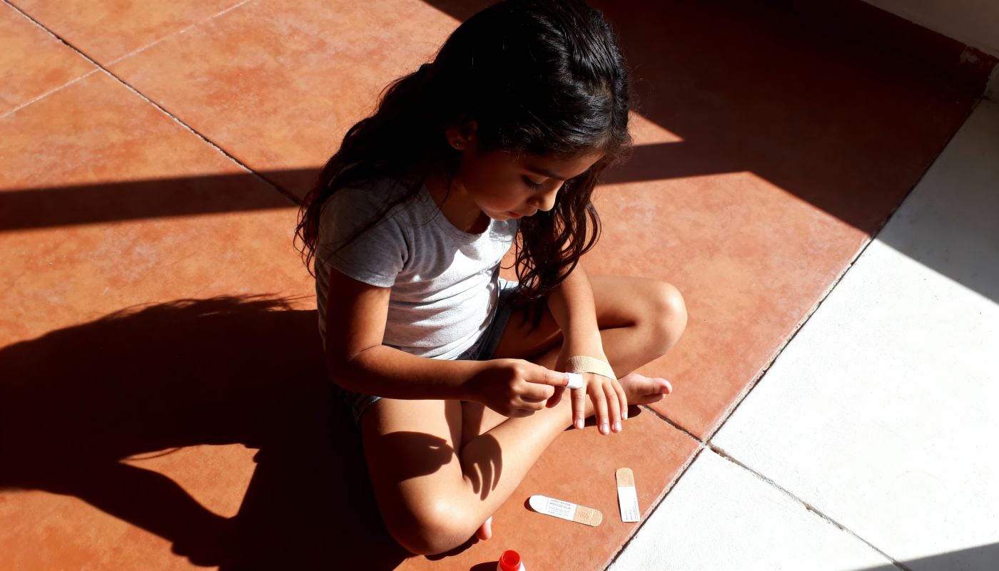 Child placing bandage on hand
