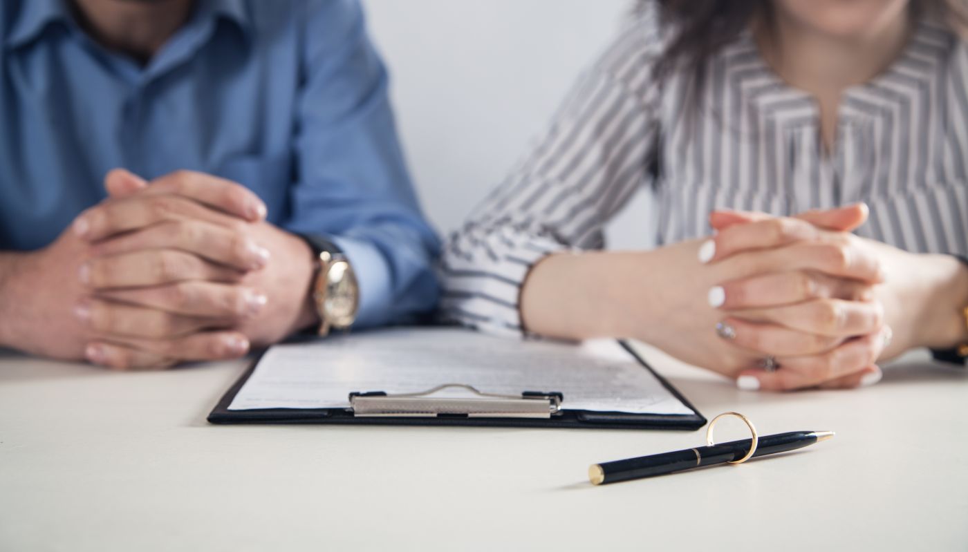 Couple with divorce contract and ring on desk