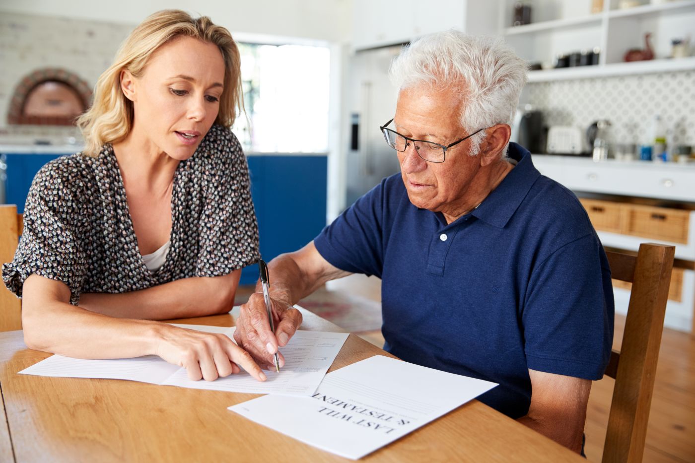 Woman Helping Senior Man To Complete Last Will And Testament