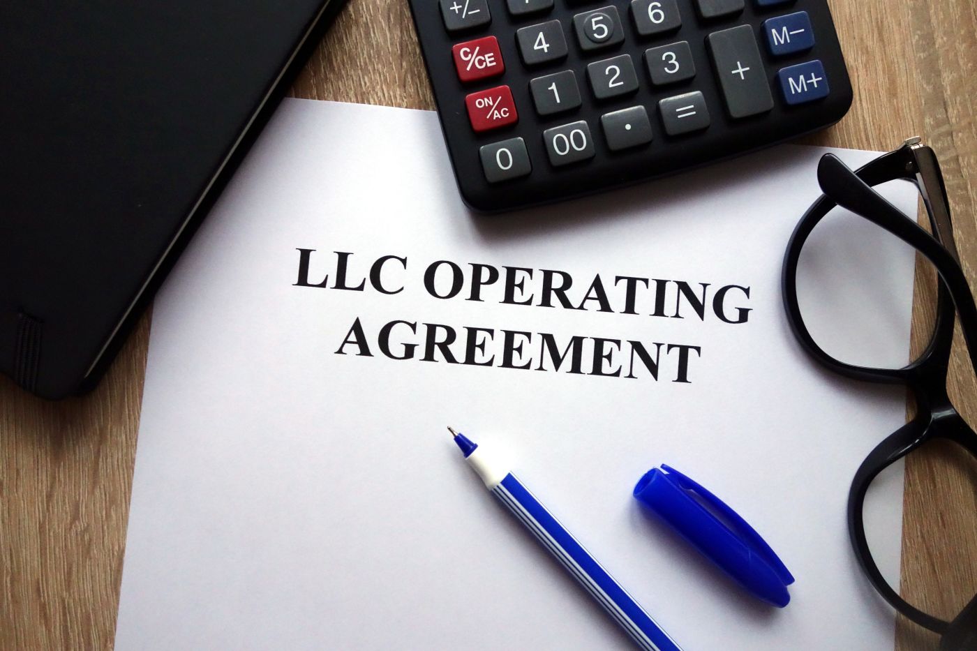LLC operating agreement, pen, glasses and calculator on desk