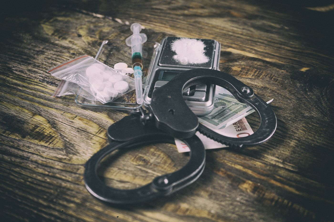 Handcuff and drugs in table