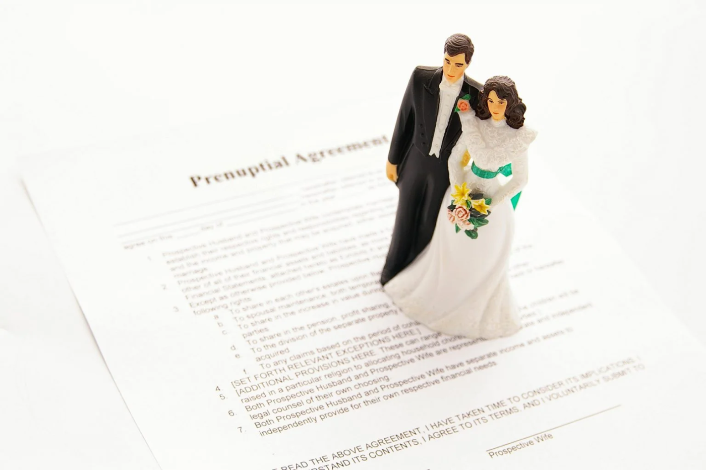 Bride and groom cake topper on prenuptial agreement