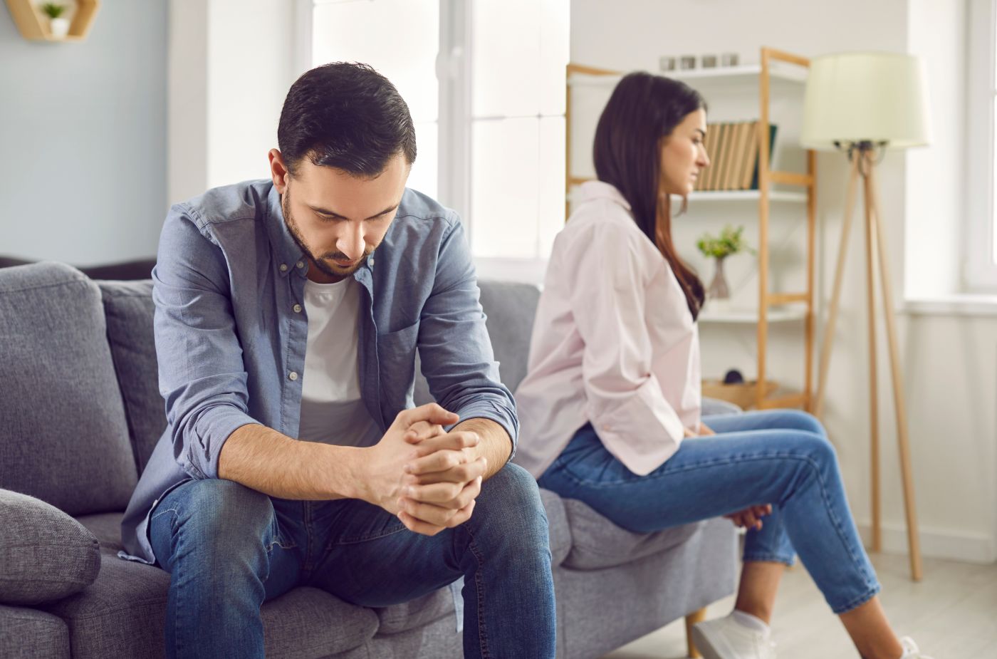 Stressed married couple sitting separately in the living room.