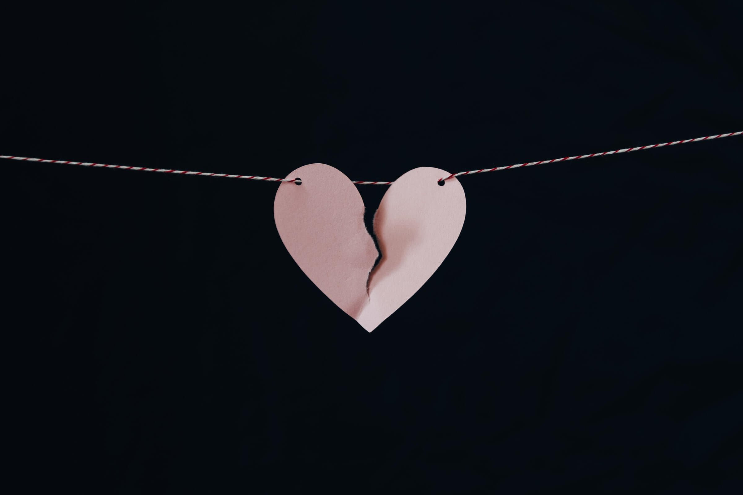 A Pink Paper Heart on a String Being Torn in Half.jpg