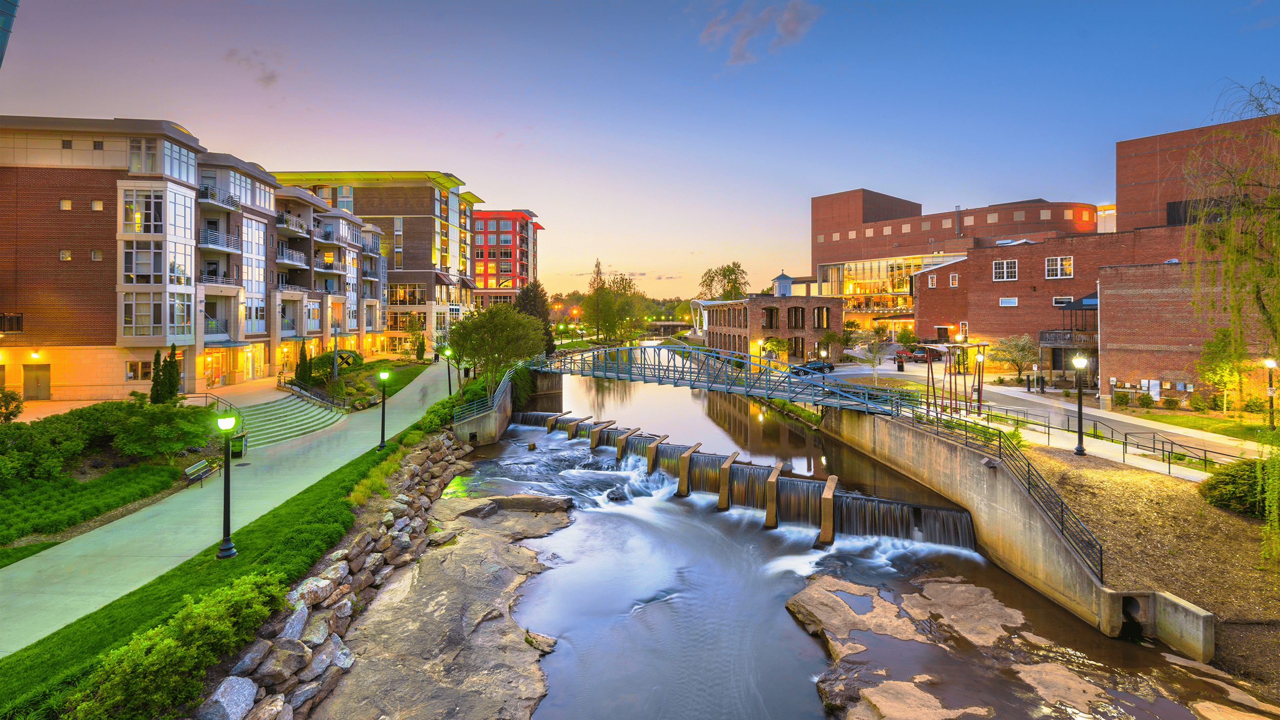 Greenville, South Carolina, USA downtown cityscape on the Reedy River at dusk