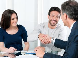 happy couple shaking hands with man in suit