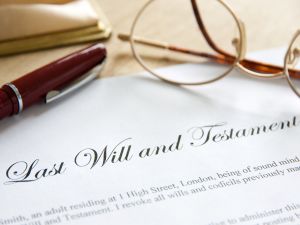 Last will and testament written on a paper with glasses and pen laid on top