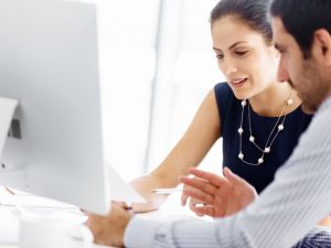 A man and a woman talking the woman is holding a piece of paper and pointing to it with a pen