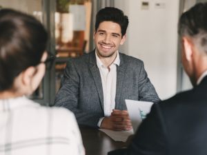 Man smiling across the table from a man and women