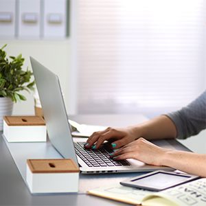 Person sitting at desk typing on laptop keyboard