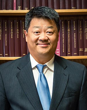 Headshot of Attorney Matthew H. Crow in front of the Bookshelves