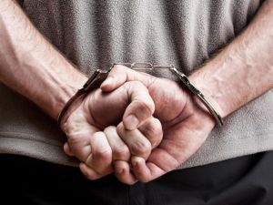 Close up of man's hands behind his back in handcuffs