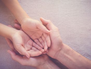 Child with it's hands in an adult's hands