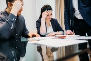 Couple filling out divorce paperwork with hands on their heads