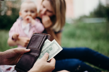 Hundred dollar bills being pulled out in front of baby and mother