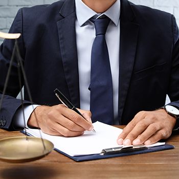 Man at his desk in a suit writing on a document