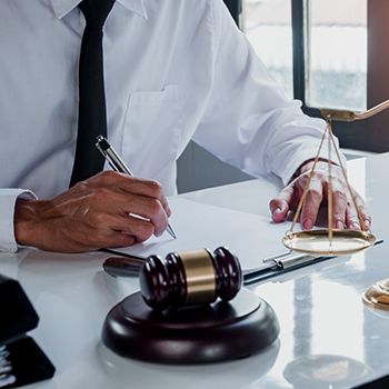 A lawyer writing at his desk with a gavel next to him