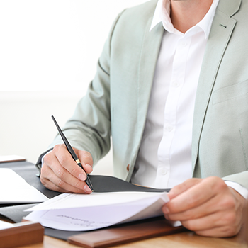 Male notary signing document at table in office