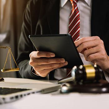 Male judge in a courtroom the gavel, working with smart phone and laptop and digital tablet computer on wood table