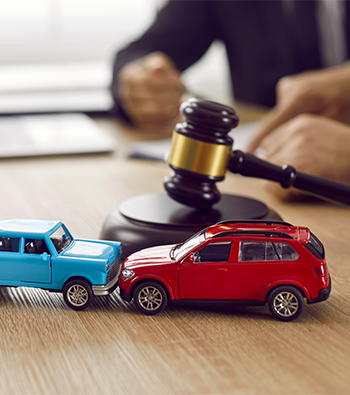Gavel and two small toy car models on desk in courthouse