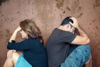 Upset Couple Sitting Back to Back on the Ground