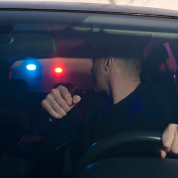 Driver with a beer bottle in hand being pulled over