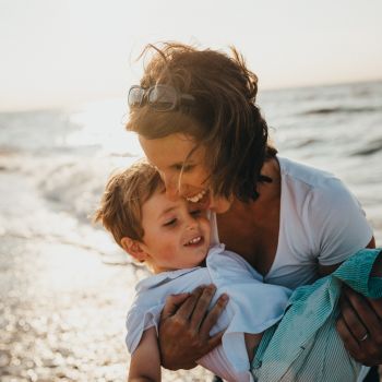 A happy woman and child holding each other on a beach