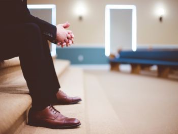 Man sitting and waiting with his hands clasped